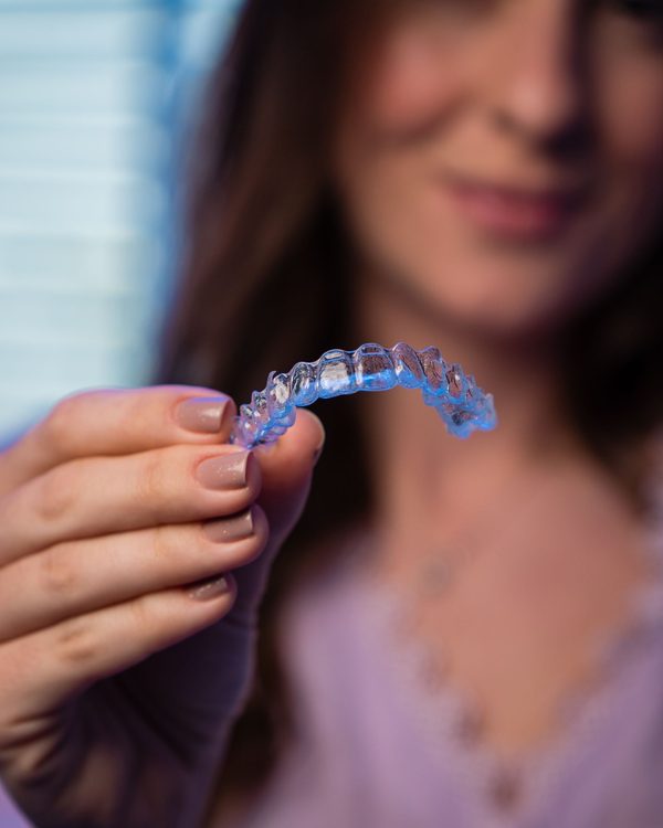 Una donna tiene in mano una mascherina trasparente per allineare i denti